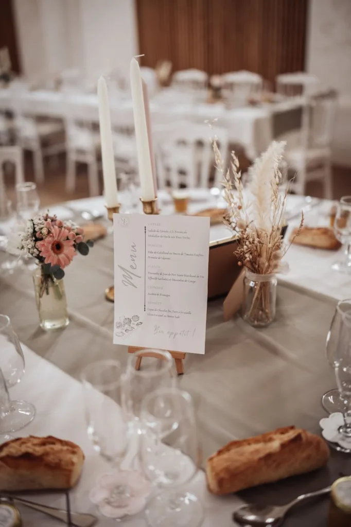 Table de mariage dressée avec menu, bougies et fleurs séchées