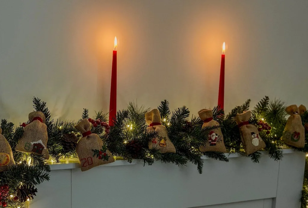 Bougies rouges et guirlande de sapin décorée de pochons brodés pour Noël